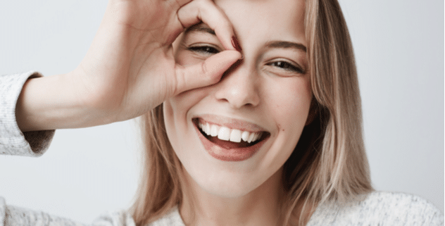 portrait of beautiful joyful blonde female smiling with fingers in okay gesture.