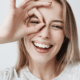 portrait of beautiful joyful blonde female smiling with fingers in okay gesture.
