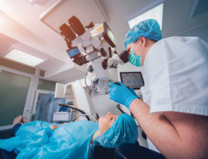 Profile of a LASIK surgeon performing bladeless LASIk surgery on a patient in a sterile room.