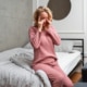 Woman sitting up in bed and rubbing at her eyes, dealing with blurry vision after waking up.